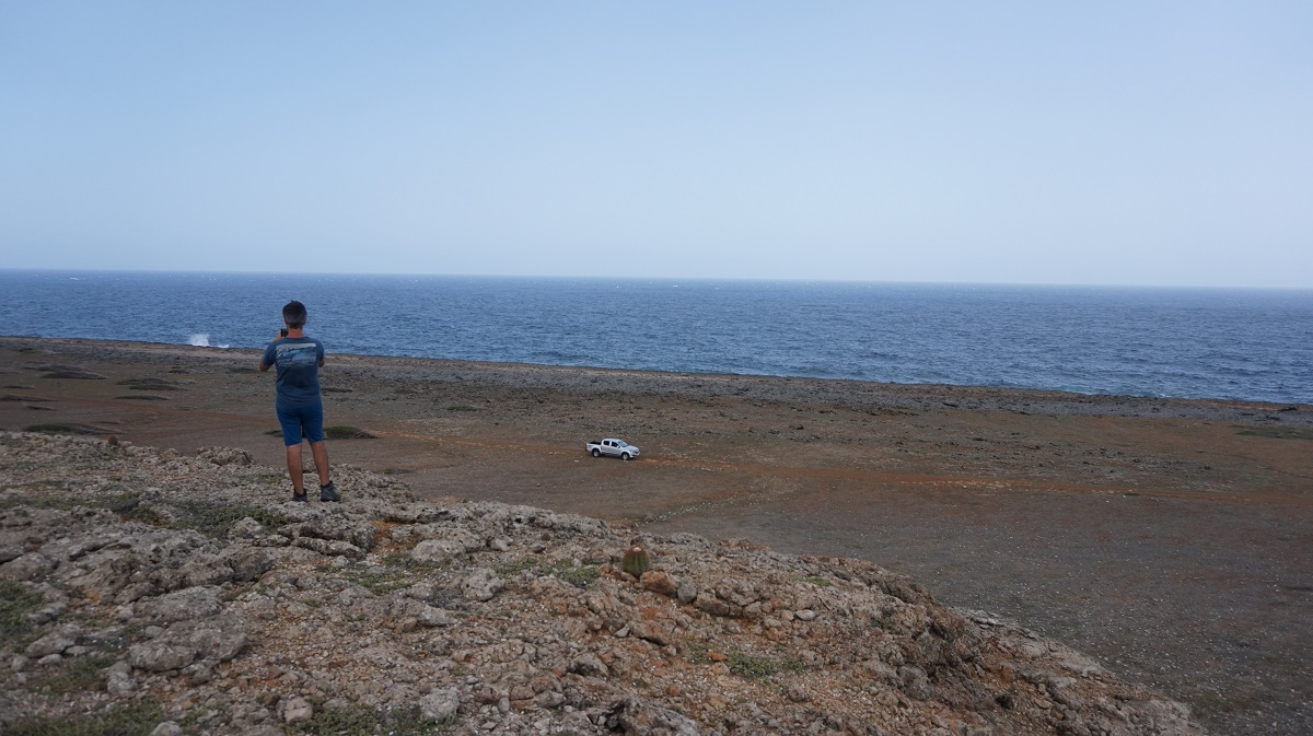 Dr. Alessio Rovere (MARUM,Bremen) is standing on the the edge of the fore reef, where waves used to break.A pick-up car is parked on top of a lower terrace that corresponds to yet another sea-level highstand. Credits: Paolo Stocchi, NIOZ 