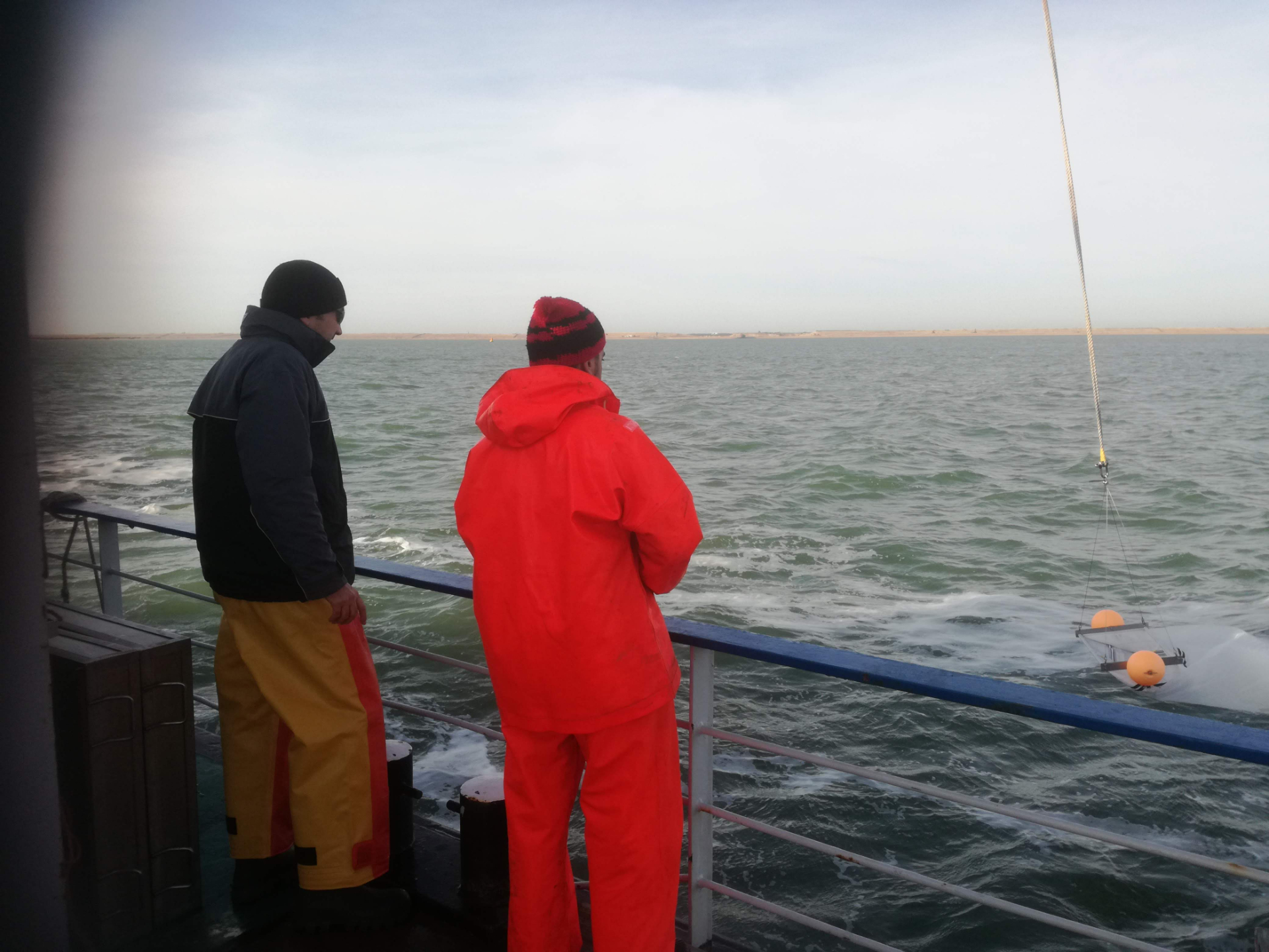 Colleagues collecting microplastics with a plankton net