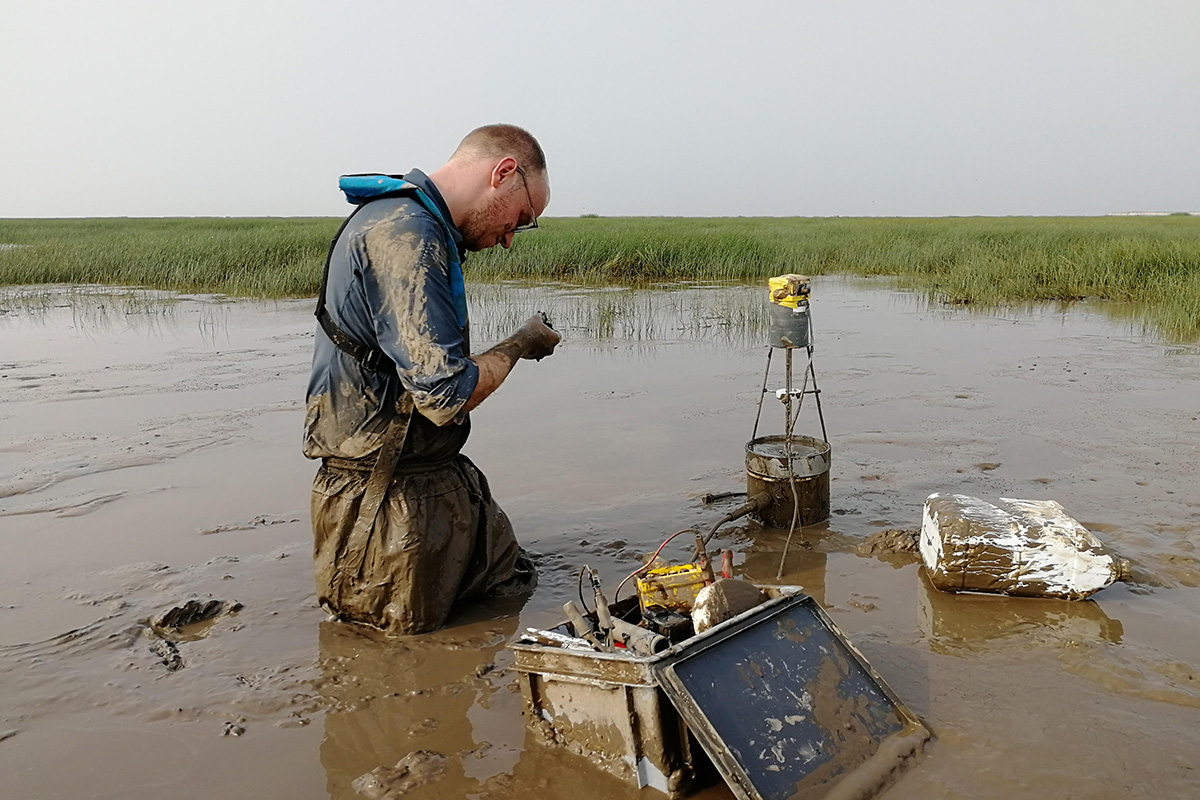 Tim Grandjean during his fieldwork, standing in a deep layer of mud