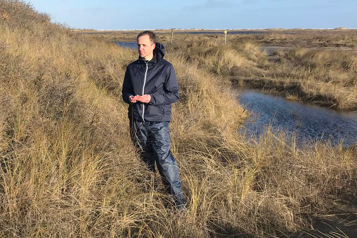 Tjisse van der Heide met fijne HDPE-plastickorrels in zijn hand die hij vond in de duinen van Schiermonnikoog. Foto: Jorien Bakker.