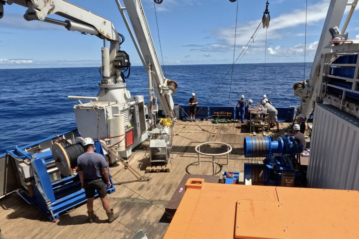 How many safety helmets can you spot. The black mooring cable is coming from the big wooden spool on the left of the picture, it then goes over the white winch on top before reaching the water. – Photo: Robin van Dijk