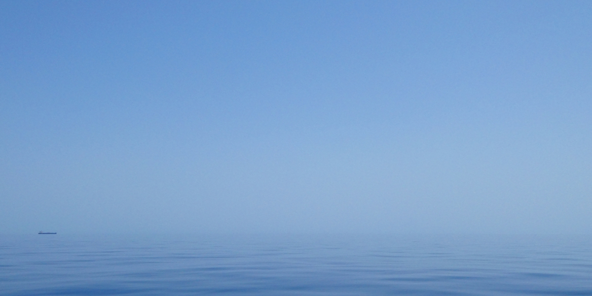 The sea is very flat and the sky very blue resulting in the horizon being hardly visible.