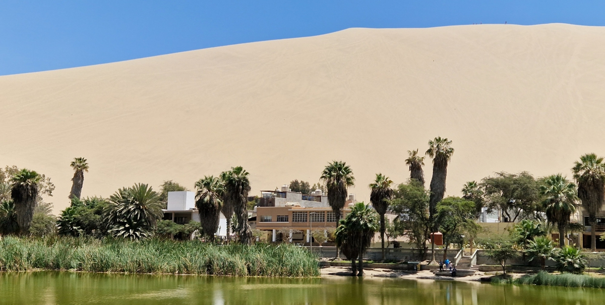 An unreal scenery with mega sand dunes threatening the tiny pool of water