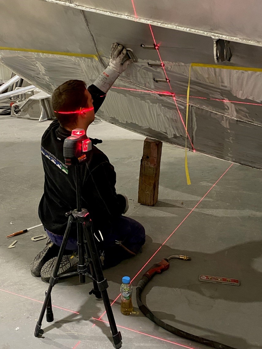 Applying the draught markings to the hull of the RV Adriaen Coenen. Red lines are laser beams used to align the markings.