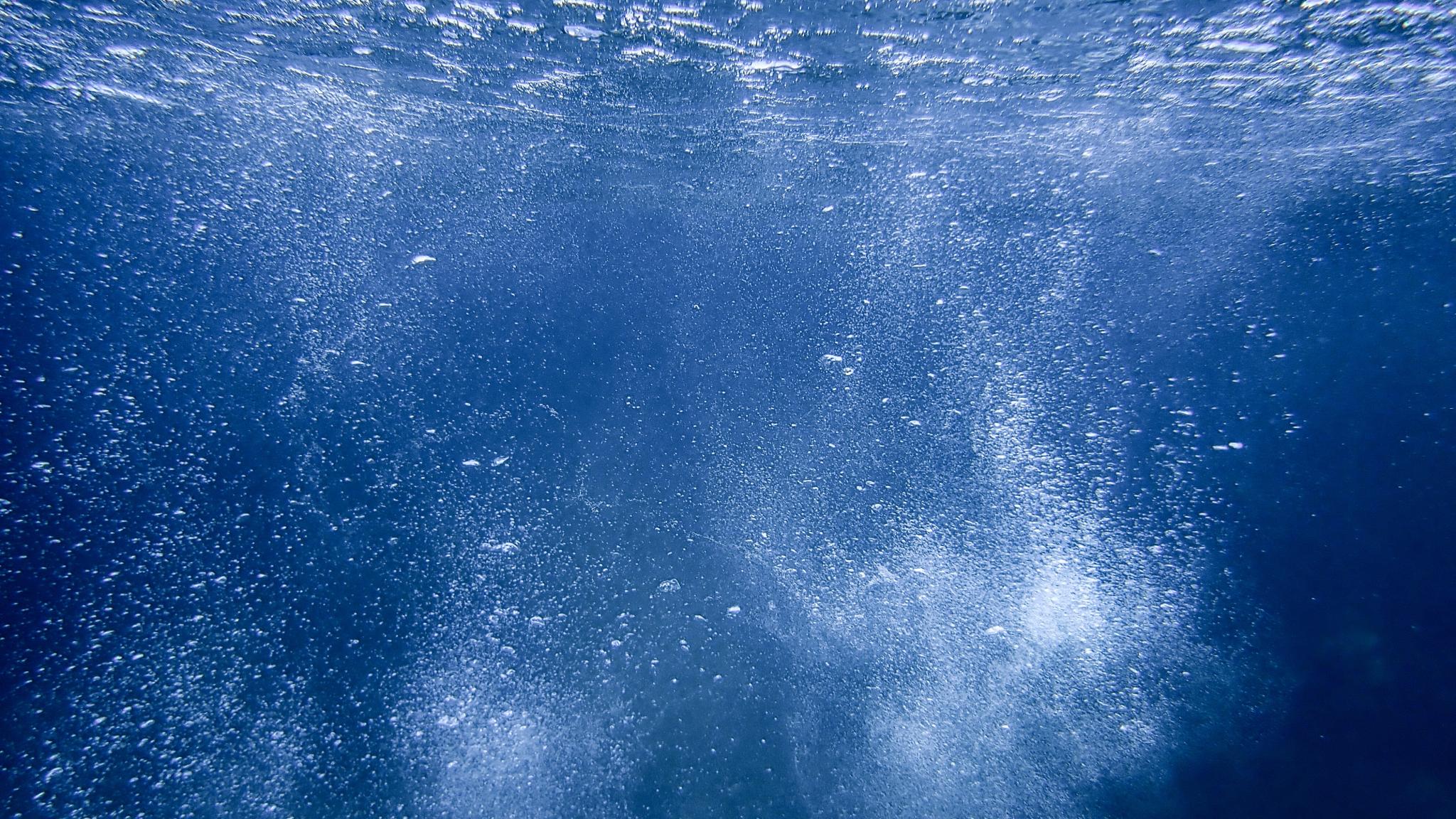 Onderwaterfoto van de waterkolom met bubbels die naar de oppervlakte stijgen.
