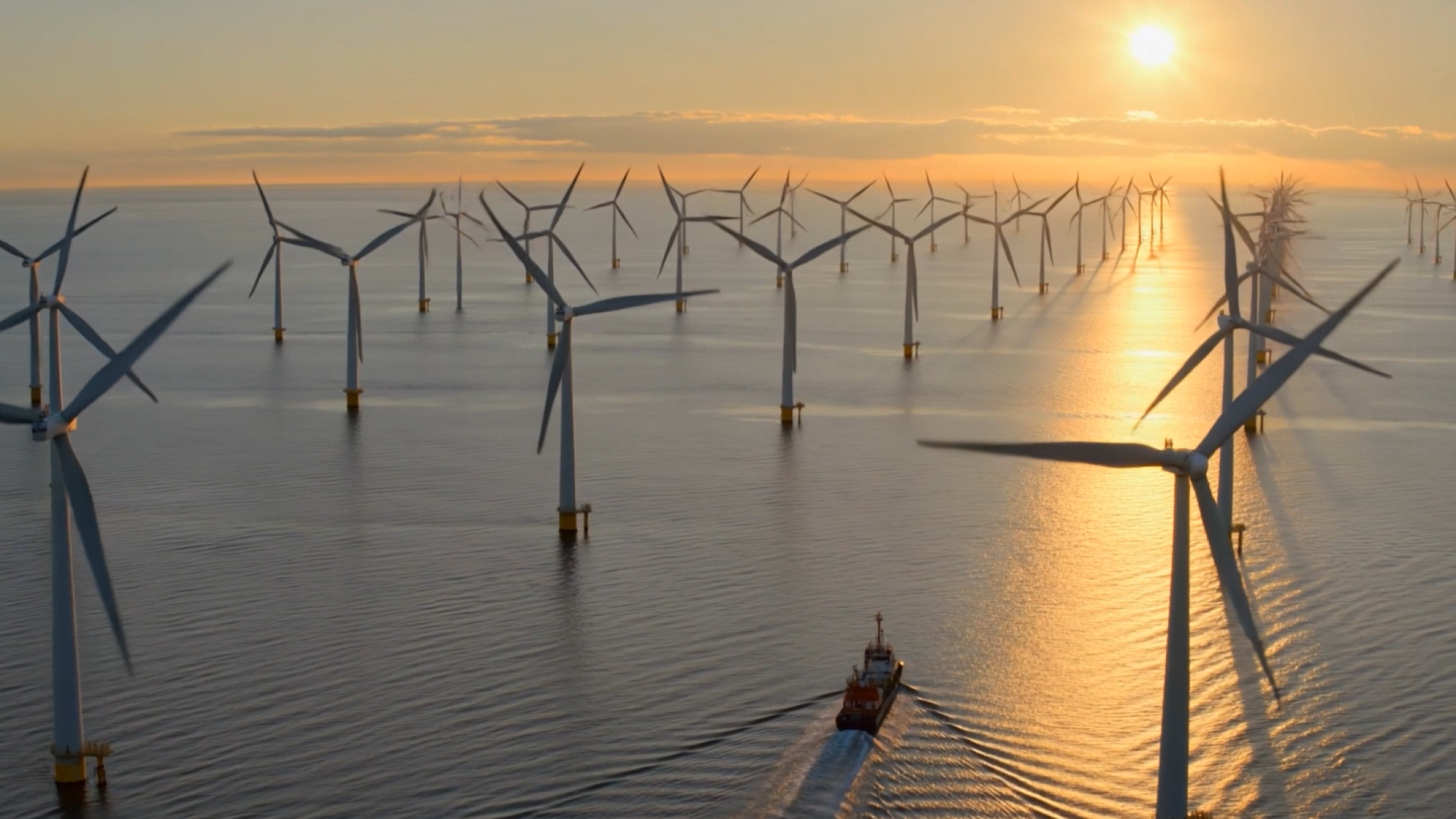 Een boot die vaart tussen de windmolens op de noordzee