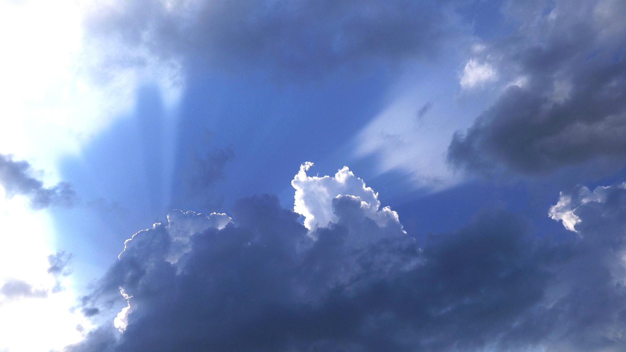 an image of clouds in front of a blue sky backdrop with sunrays