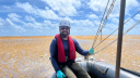 Fabio Nauer sits in a zodiac boat among vast Sargassum mats while collecting samples at sea.