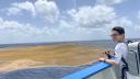 Scientist Sully Sullivan stands on the deck of a ship beside a vast floating Sargassum patch while preparing for a measurement.