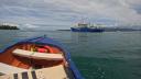 Research vessel Pelagia sails away from the port of Pointe-à-Pitre, seen from a small boat on calm water.