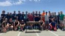 Een grote groep mensen poseert op het achterdek van een schip in mooi weer