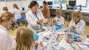 Kinderen en een volwassene zijn aan het knutselen zittend aan een tafeltje