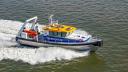 The research vessel RV Adriaen Coenen speeds across the water, leaving a foamy wake.