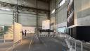 Exhibition space featuring large maps, information panels and a row of black viewing boxes at the International Architecture Biennale Rotterdam.
