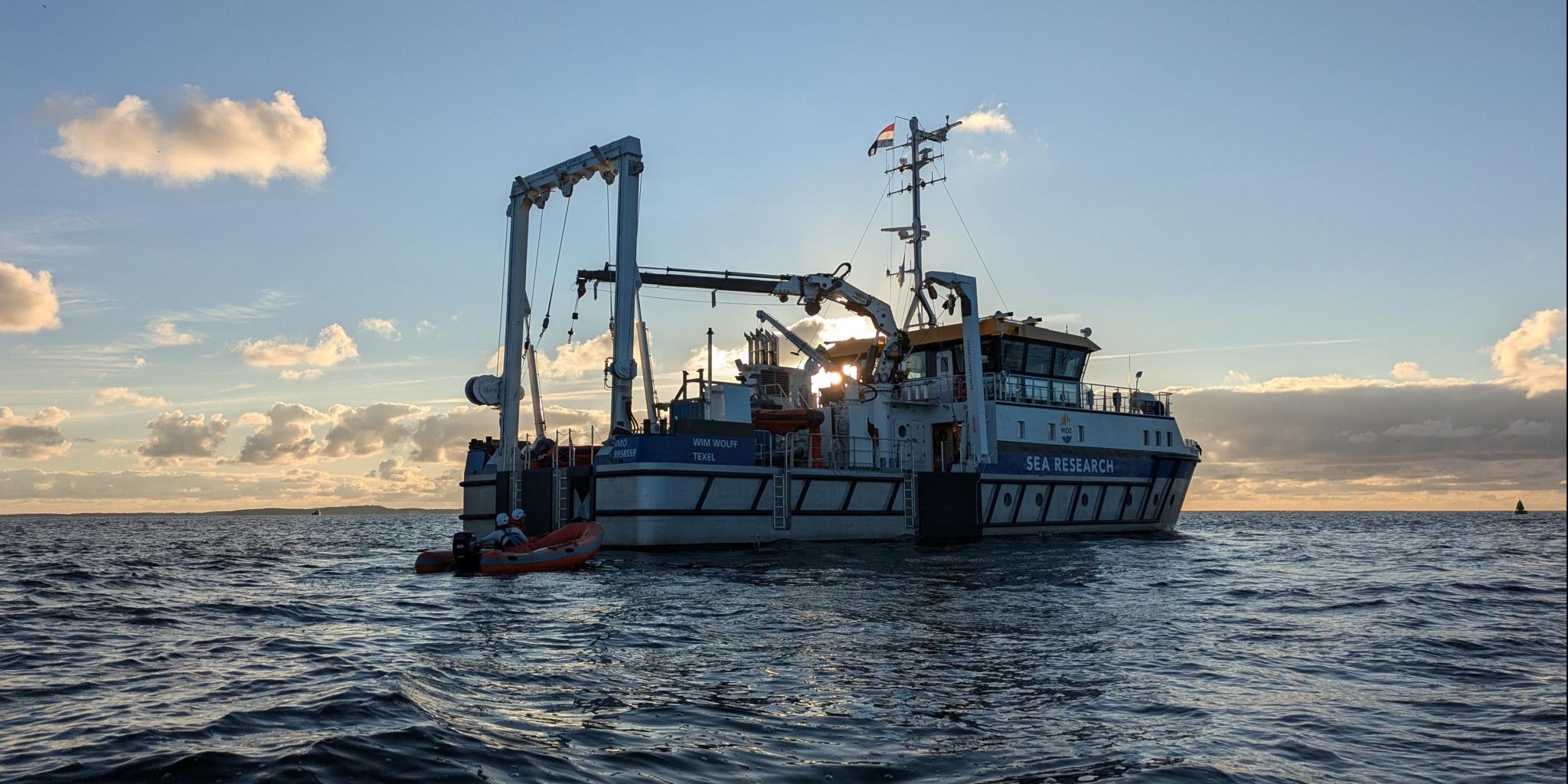 Het schip RV Wim Wolff, gezien tijdens een vaart op een kalme zee, vlak voor zonsondergang.