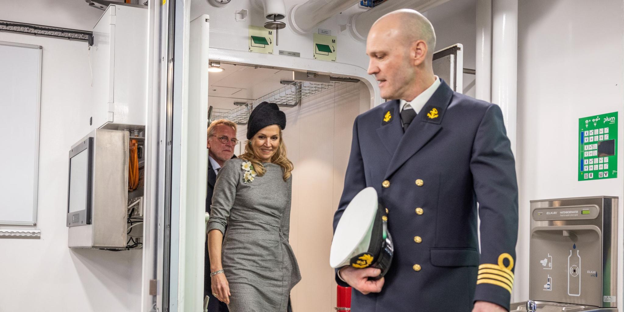 De kapiteitn passeert een deur, gevolgd door de koningin en de NIOZ-directeur