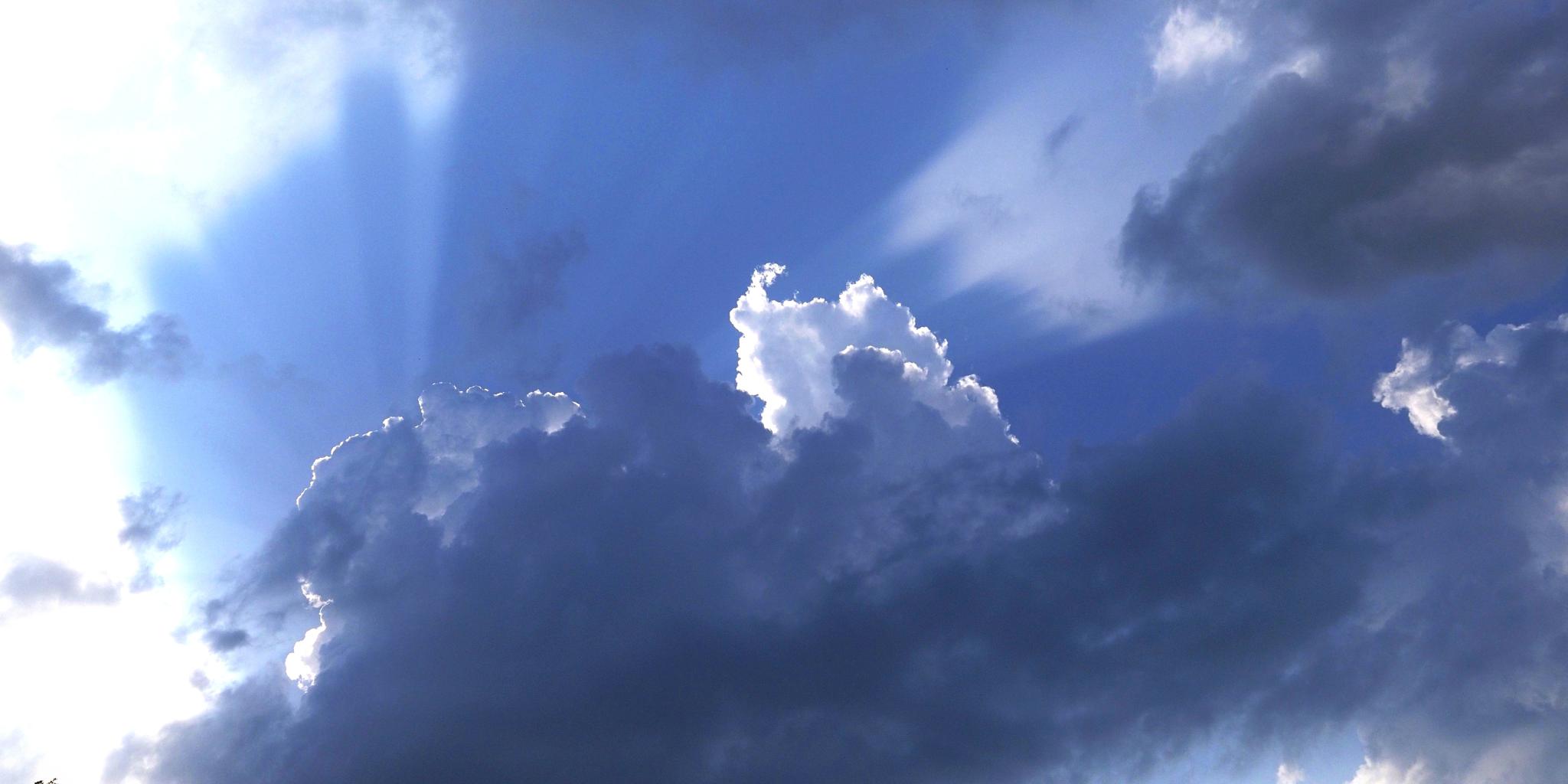 an image of clouds in front of a blue sky backdrop with sunrays