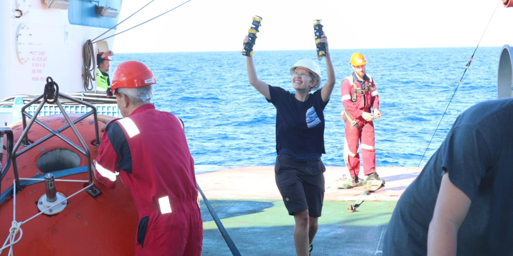 Young person catches two measuring tools hanging on ropes on a research vessel