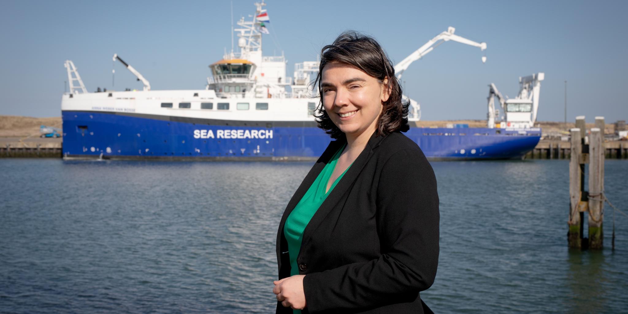 A portrait of researcher Sabine Gollner in front of the research vessel RV Anna Weber-van Bosse, anchored in the NIOZ harbour, Texel.