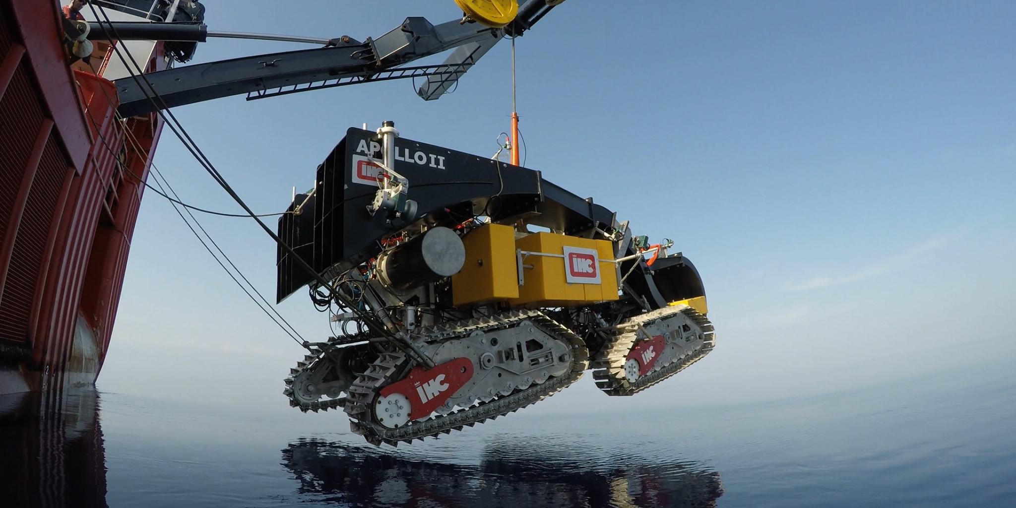 Deployment of Apollo II, a tracked vehicle being lowered over the sea by a crane.