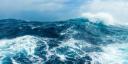 A photo of a stormy ocean, with a big wave splashing in the front