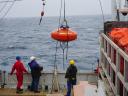 A measuring instrument being lowered from a research vessel to collect research data.