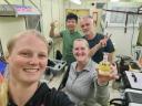 Vier mensen in een laboratorium kijken lachend in de camera