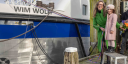 Caroline Visser of NWO and Charly Wolff stand beside the research vessel RV Wim Wolff during its christening ceremony. Together they hold the ceremonial ribbon, with the vessel's name visible in the background.