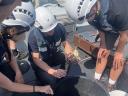 Researchers wearing safety helmets examine a crab on board the RV-HA1 Wantij, checking it for parasites as part of field research.