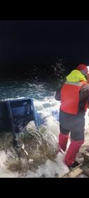 Researcher collecting water samples from the CTD on deck during rough sea conditions.