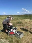 Twee onderzoekers controleren en ordenen hun bemonsteringsapparatuur in het gras voordat ze op pad gaan.