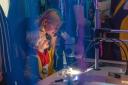 Woman and boy watch through a microscope in purple deepsea setting